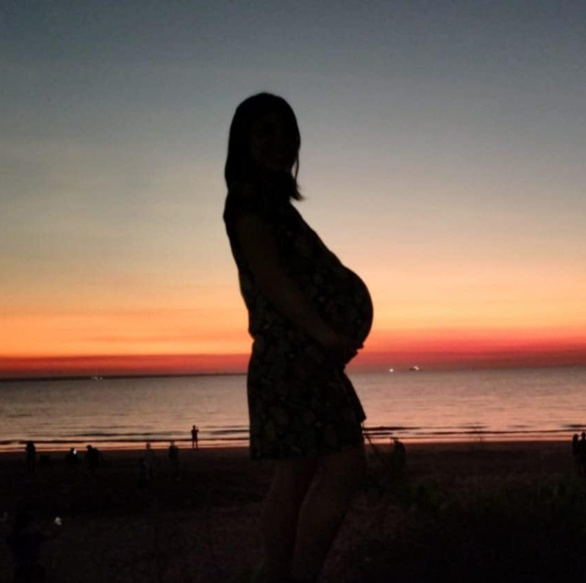 Silhouette of a person against a sunset sky over water